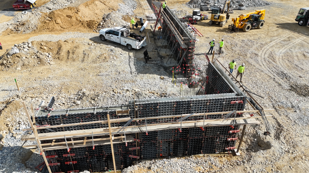 Formwork prepared for a large concrete foundation wall on an active construction site.
