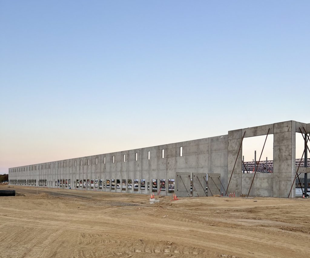 Front view of a fully erected tilt-up building featuring reveals and cutouts with a sunrise in the background.