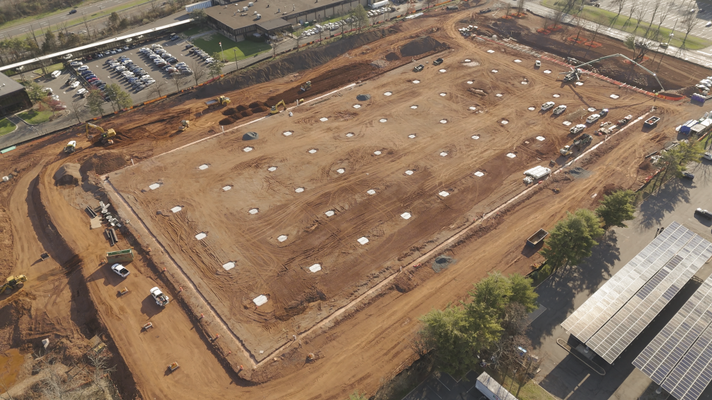 Aerial view of a large construction site showing concrete foundations for a future building.