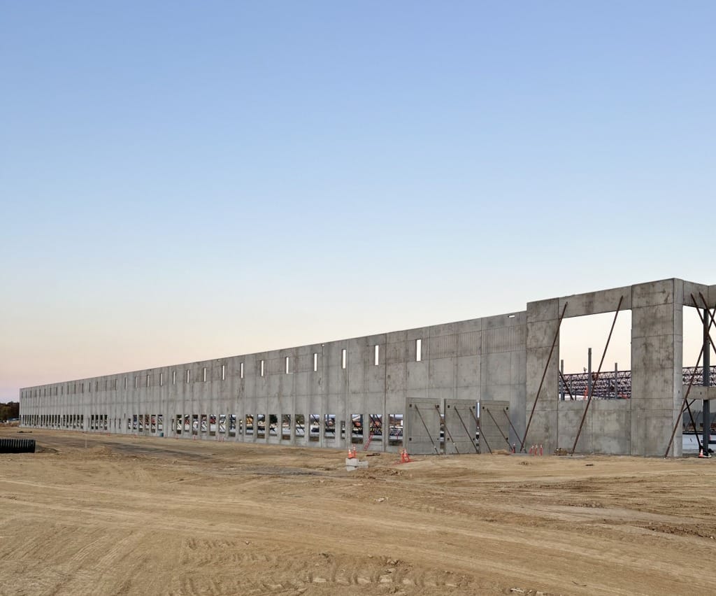 Front view of a fully completed tilt-up building featuring reveals and cutouts with a sunrise in the background.
