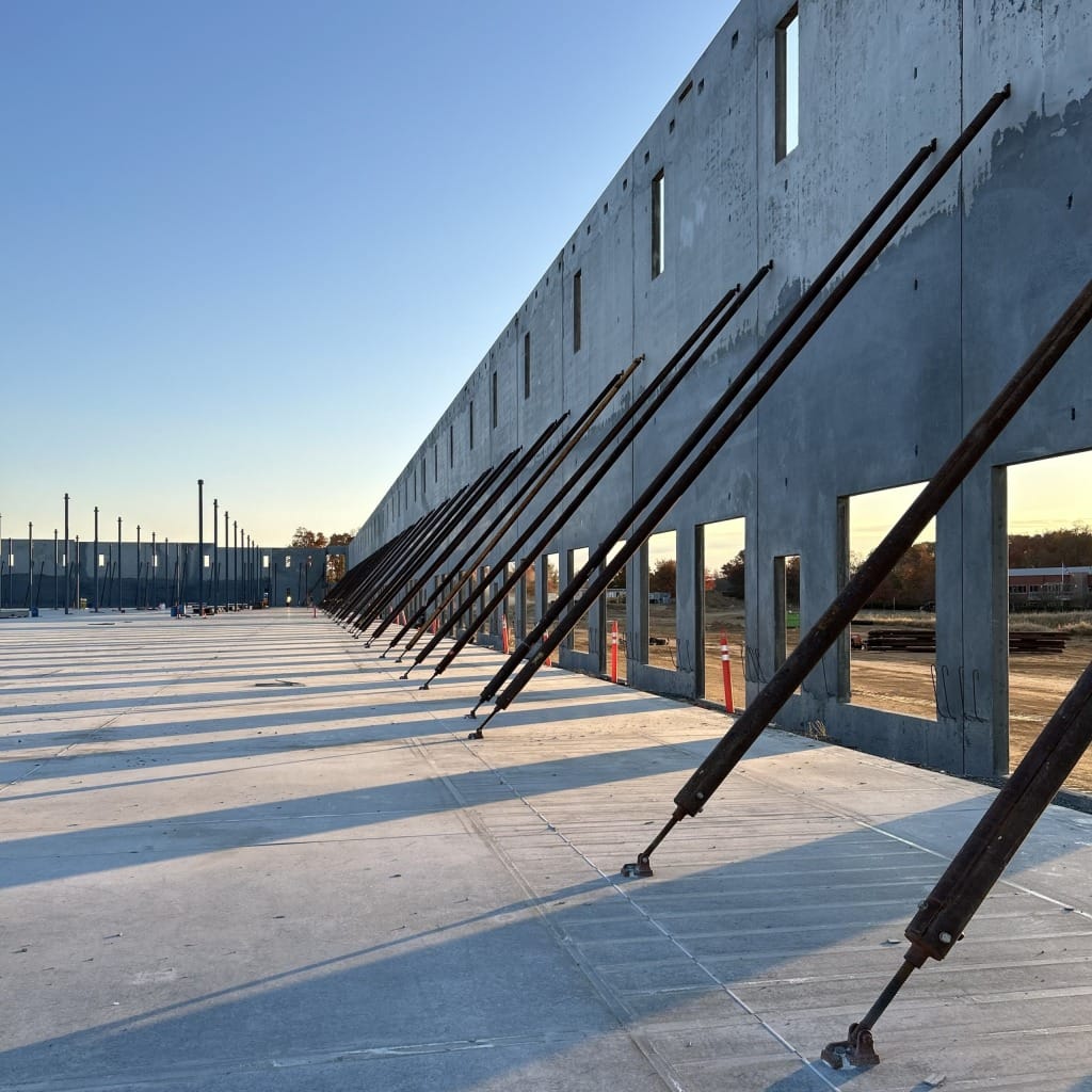 Concrete tilt-up wall being supported by tilt-up wall braces, with sun shining through the cutouts.
